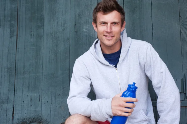 Retrato de un joven atleta guapo sosteniendo una botella de agua —  Fotos de Stock