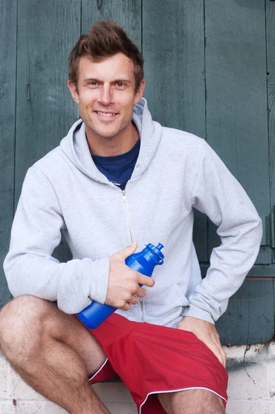 Yakışıklı bir genç atlet su şişesi holding portresi — Stok fotoğraf