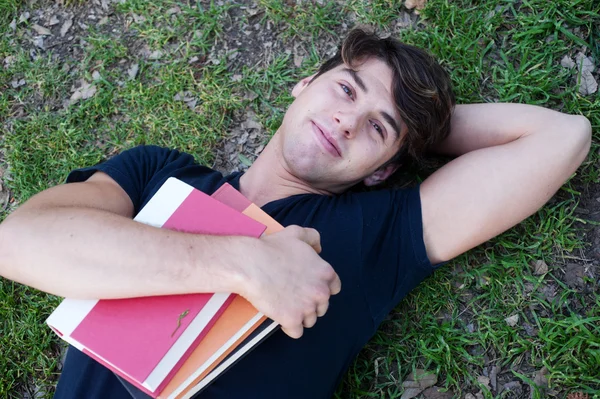 젊은 남성 학생도 서와 함께 잔디에 누워 — 스톡 사진