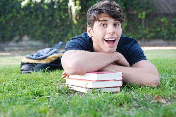 Jonge mannelijke student liggend op gras met boeken — Stockfoto
