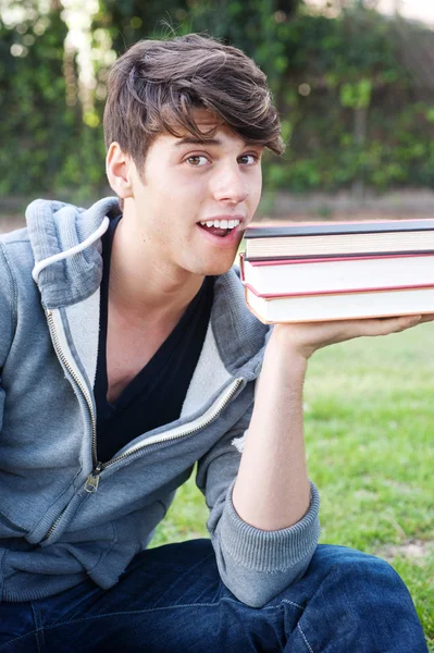 Kitaplar çimenlerin üzerinde genç erkek öğrenci — Stok fotoğraf