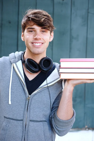 Νέος άνθρωπος που κρατά τα βιβλία με τα ακουστικά — Φωτογραφία Αρχείου