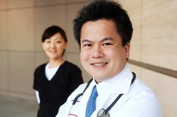 Azjatycki lekarz z pielęgniarką w tle — Zdjęcie stockowe