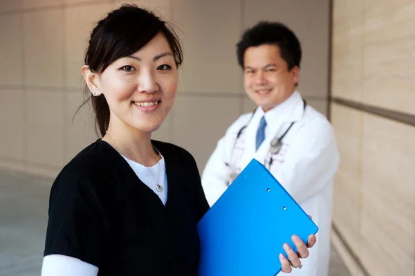 Asiatico infermiera con medico in background — Foto Stock