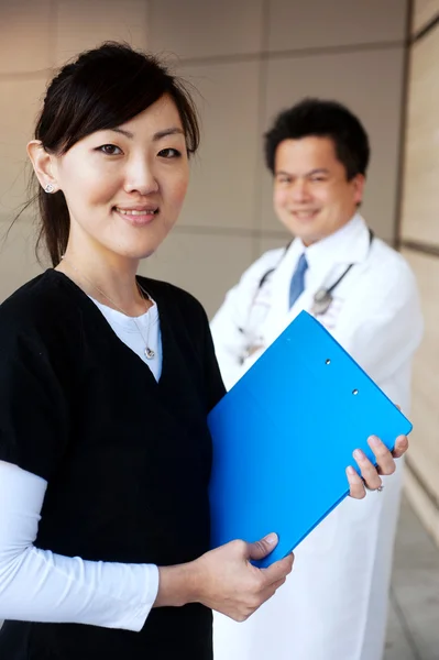 Azjatycka pielęgniarka z lekarzem w tle — Zdjęcie stockowe