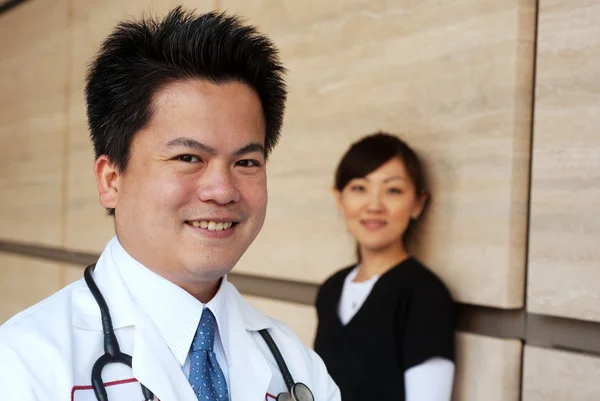Azjatycki lekarz z pielęgniarką w tle — Zdjęcie stockowe
