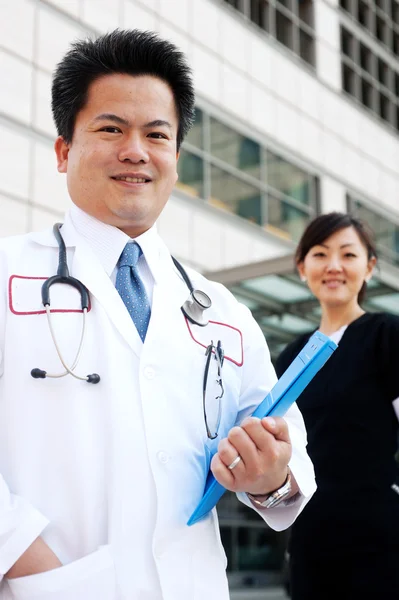 Médico asiático con enfermera en segundo plano —  Fotos de Stock