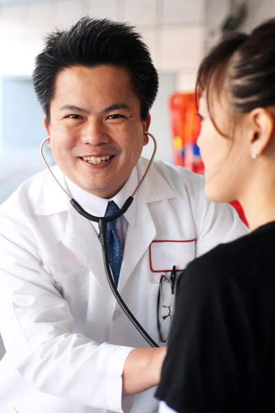 Азиатский врач со стетоскопом проверяет пациента — стоковое фото