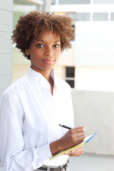 Jolie exécutive afro-américaine avec stylo et papier — Photo