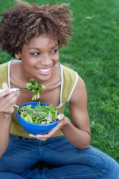 Bella donna afroamericana mangiare un'insalata Immagine Stock