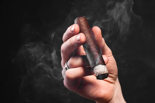 Мужчина держит курящую коричневую сигару — стоковое фото