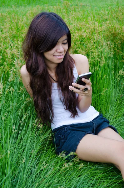 Aziatische schattig meisje texting op weide — Stockfoto