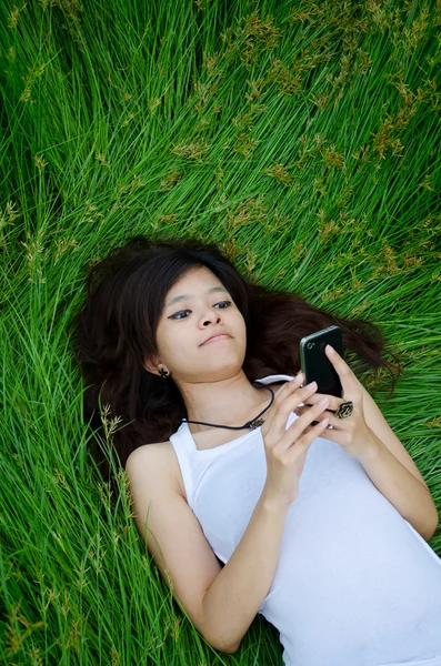 Asiático bonito menina mensagens de texto no prado — Fotografia de Stock