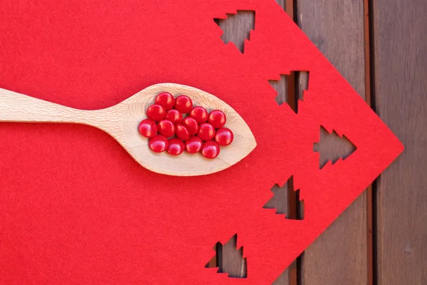 Wooden spoon with red candies — Stok fotoğraf