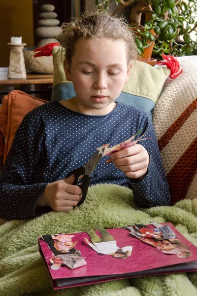 Menina jovem cortando bonecas de papel — Fotografia de Stock