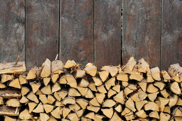 Bella immagine di sfondo con legna da ardere contro una vecchia parete di legno Immagini Stock Royalty Free