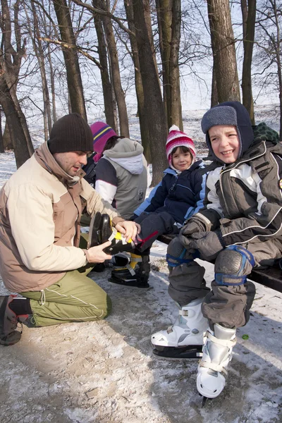 Father help children to wear skates — Stock Photo, Image
