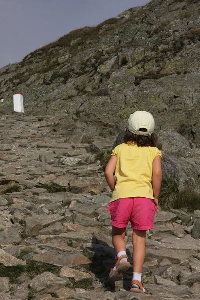 小さな女の子だけで岩が多い峰に登る — ストック写真