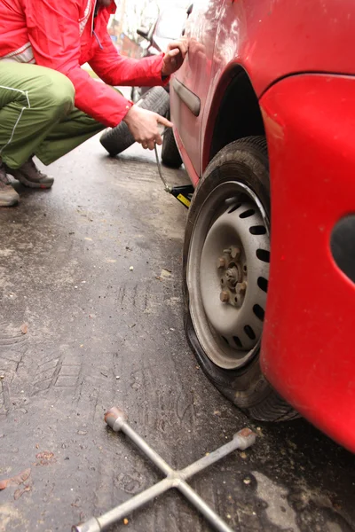 Hombre cambiando un neumático en la calle — Foto de Stock