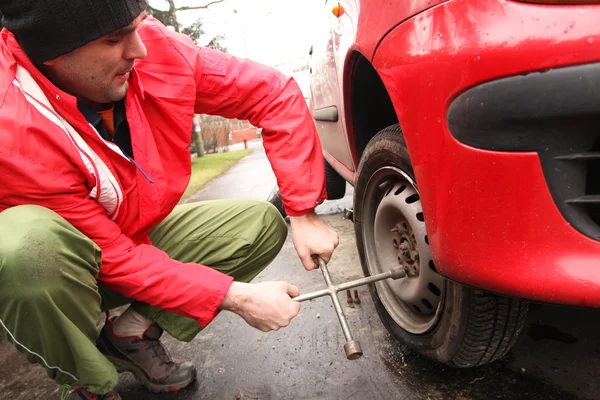 Homem trocando um pneu na rua — Fotografia de Stock