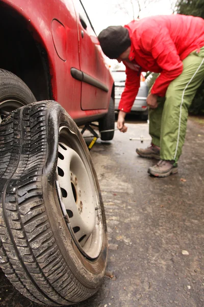 Hombre cambiando un neumático en la calle —  Fotos de Stock