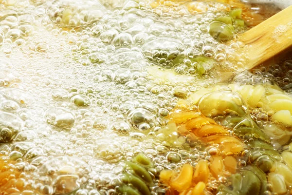Pâtes en spirale dans l'eau bouillante chaude — Photo