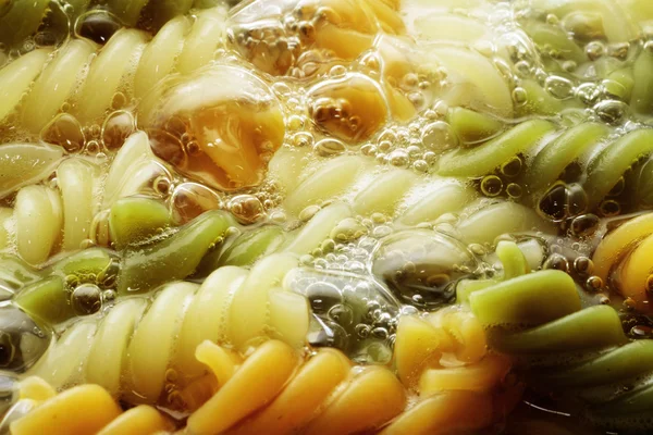 Spiral pasta in boiling hot water Royalty Free Stock Images