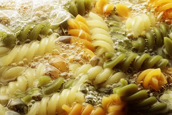 Spiral pasta in boiling hot water Royalty Free Stock Photos