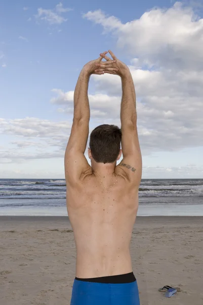 Young man stretching at the beach — Stock Photo, Image