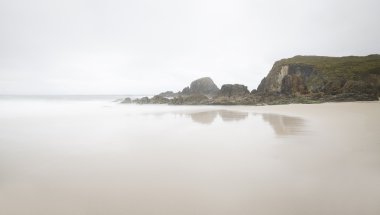 Beach on a foggy day some rocks clipart