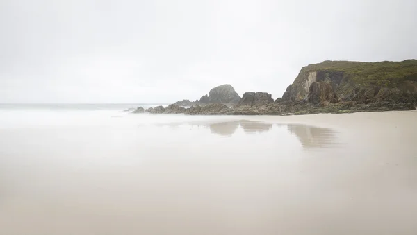 Playa en un día de niebla algunas rocas — Foto de Stock