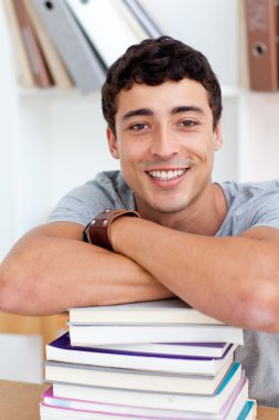 Smiling teeenager studying lots of books clipart