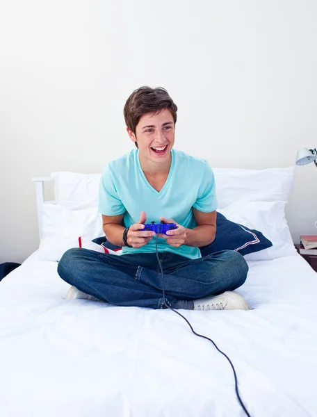 Teenager playing video games on his bed — Stock Photo, Image