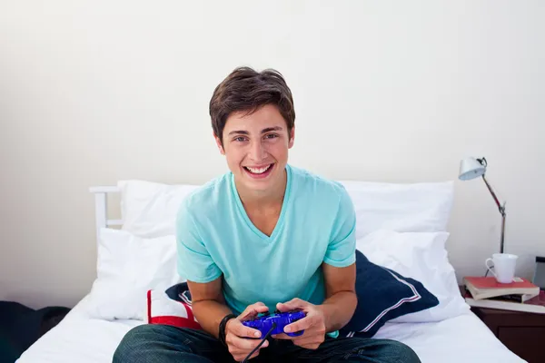 Lycklig tonåring spelar TV-spel i sitt sovrum — Stockfoto