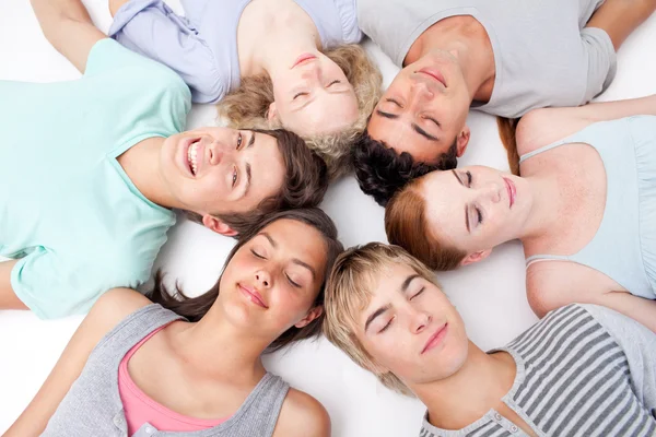 Adolescentes deitados no chão com as cabeças juntas — Fotografia de Stock