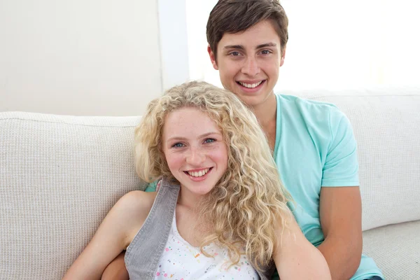 Happy couple of teens sitting on the sofa — Stock Photo, Image