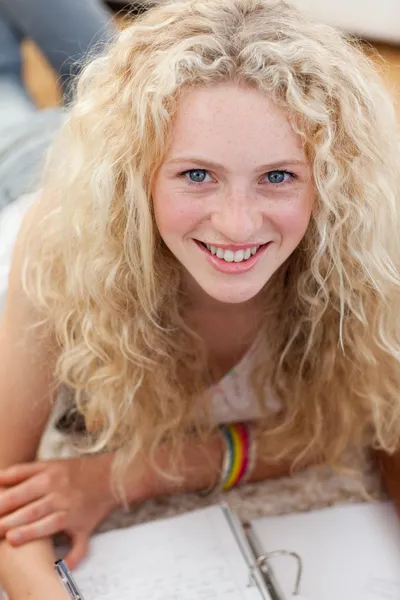 Retrato de um adolescente sorrindo estudando no chão — Fotografia de Stock