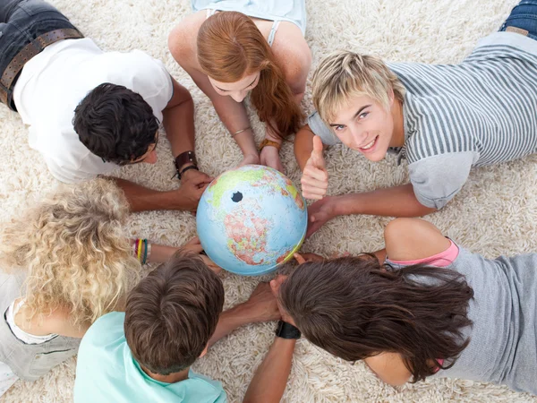 Grupo de adolescentes no chão examinando um mundo terrestre e — Fotografia de Stock