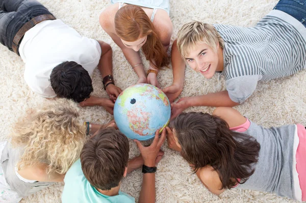 Grupo de adolescentes en el suelo examinando un mundo terrestre —  Fotos de Stock