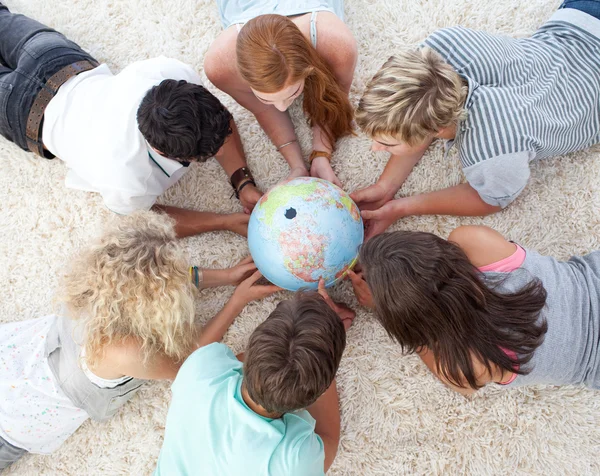 Grupo de adolescentes en el suelo examinando un mundo terrestre — Foto de Stock