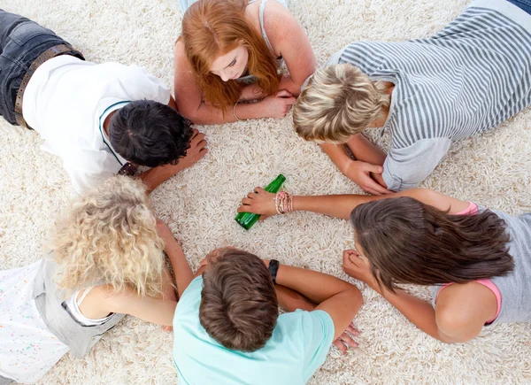 Grupp tonåringar leker med en flaska på golvet — Stockfoto