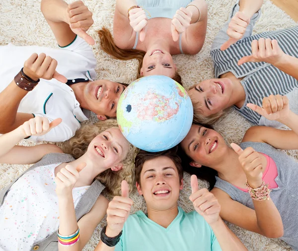 Tonåringar på golvet med en terrestrial globe i mitten ett — Stockfoto