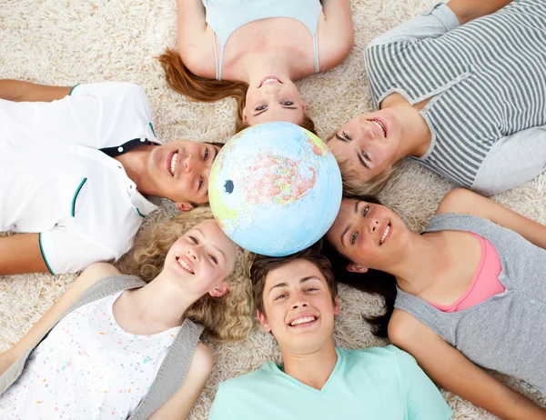 Adolescentes no chão com um globo terrestre no centro — Fotografia de Stock
