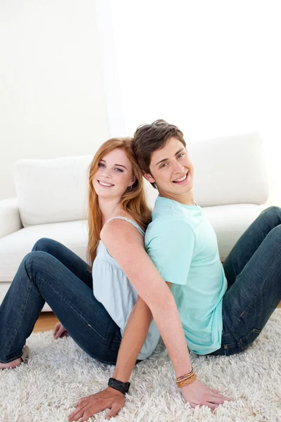 Um casal sorridente de adolescentes sentados no chão — Fotografia de Stock