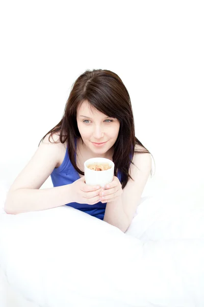 Uśmiechający się atrakcyjną kobietą, picie kawy, siedząc na łóżku — Zdjęcie stockowe