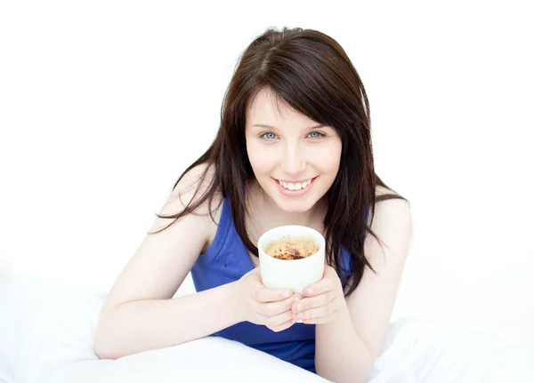 Веселая женщина пьет кофе сидя на кровати — стоковое фото