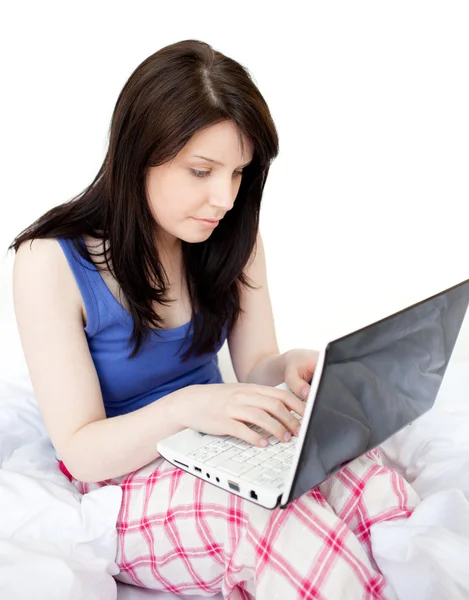 Yatağın üzerine oturan bir dizüstü bilgisayar kullanan kadın konsantre — Stok fotoğraf