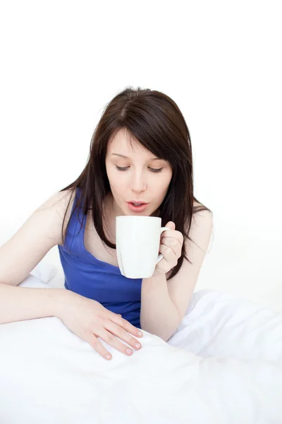 Νεαρή γυναίκα που πίνει καφέ κάθεται στο κρεβάτι — Φωτογραφία Αρχείου
