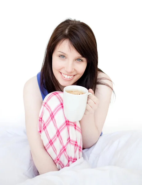 Brünette Frau trinkt Kaffee sitzend auf dem Bett — Stockfoto