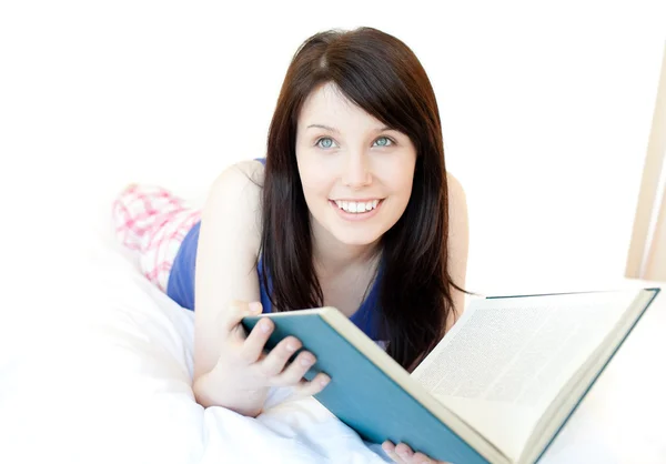 Porträt einer attraktiven Teenagerin, die auf einem Bett liegend studiert — Stockfoto